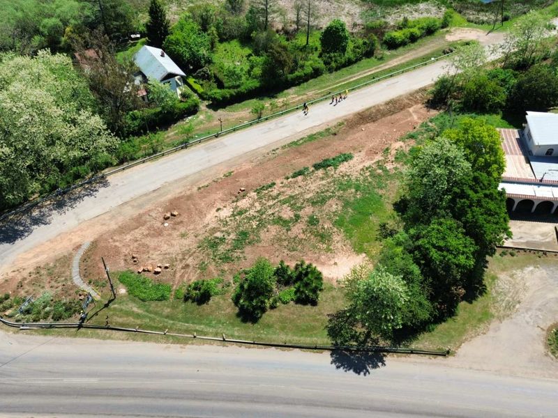 Aerial view of a vacant commercial land plot featuring road access and established greenery, suitable for development.