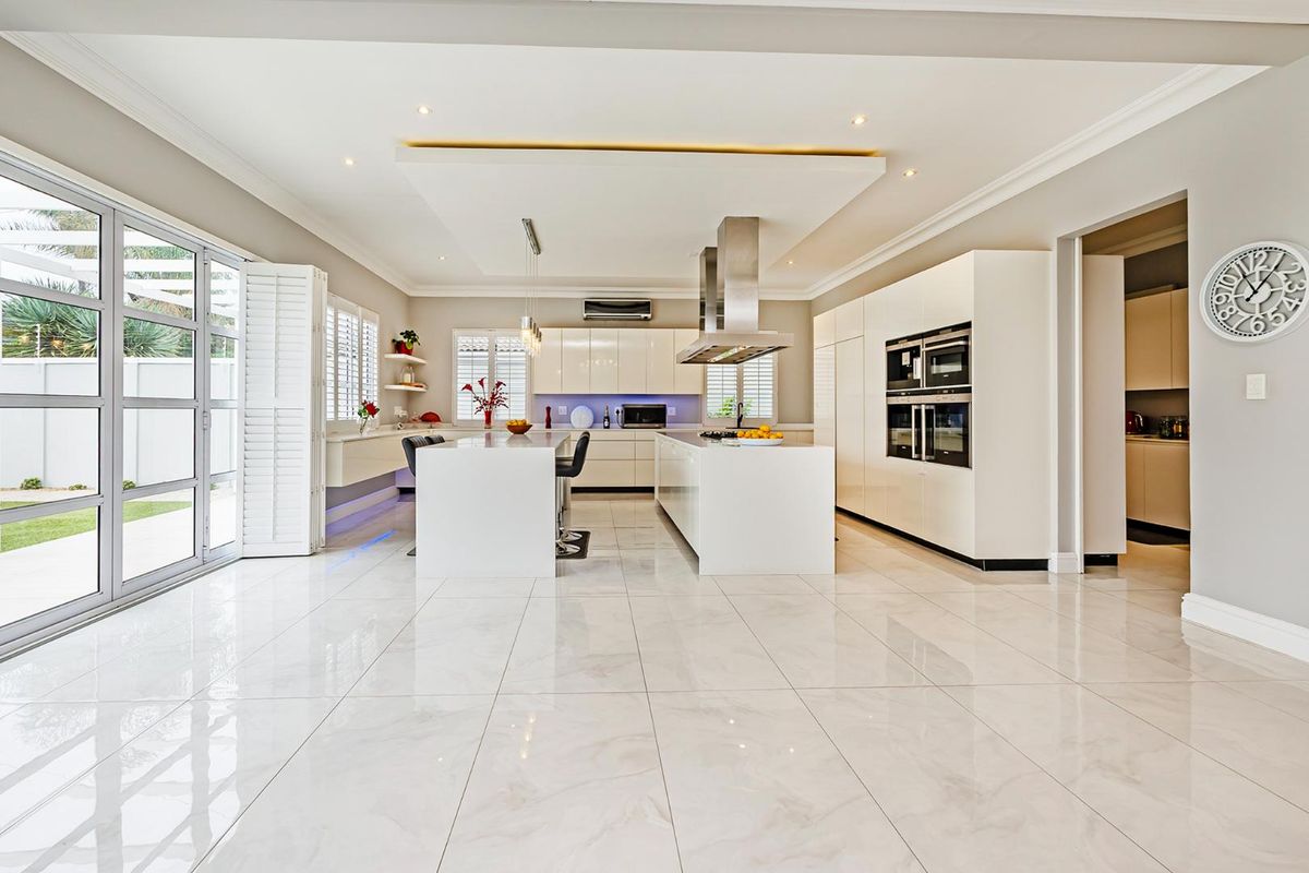 Modern, spacious kitchen featuring a large island, high-gloss cabinetry, built-in appliances, and seamless access to the outdoor patio area.