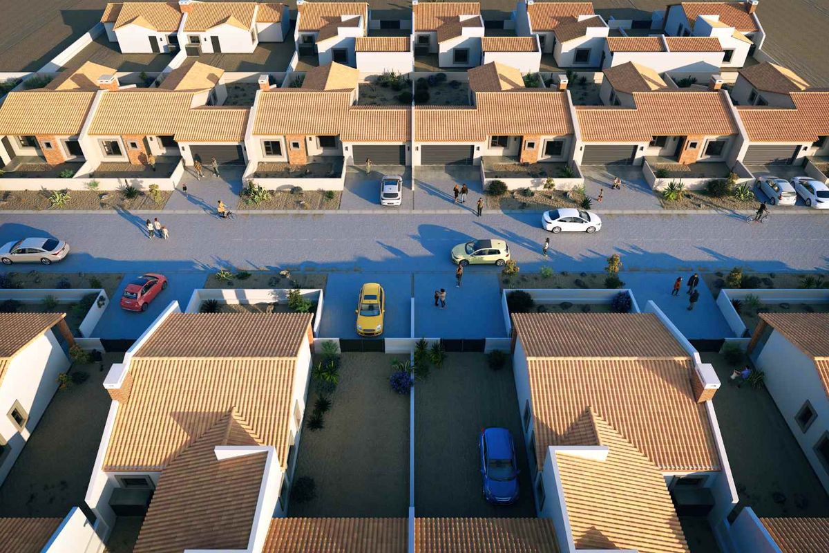 An aerial view of a modern residential housing development featuring uniform architectural design, tiled roofs, and paved street access.