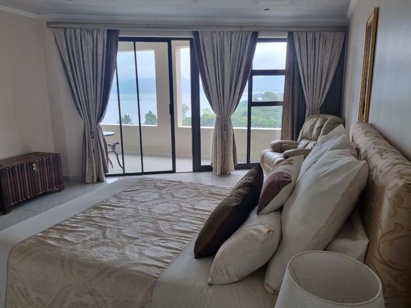 Spacious bedroom featuring large sliding glass doors that open onto a private balcony with scenic views.