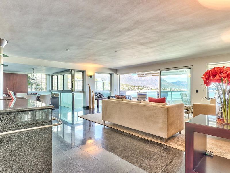 Spacious open-plan living area featuring polished stone floors, a modern granite kitchen island, and large sliding doors opening to a scenic balcony view.