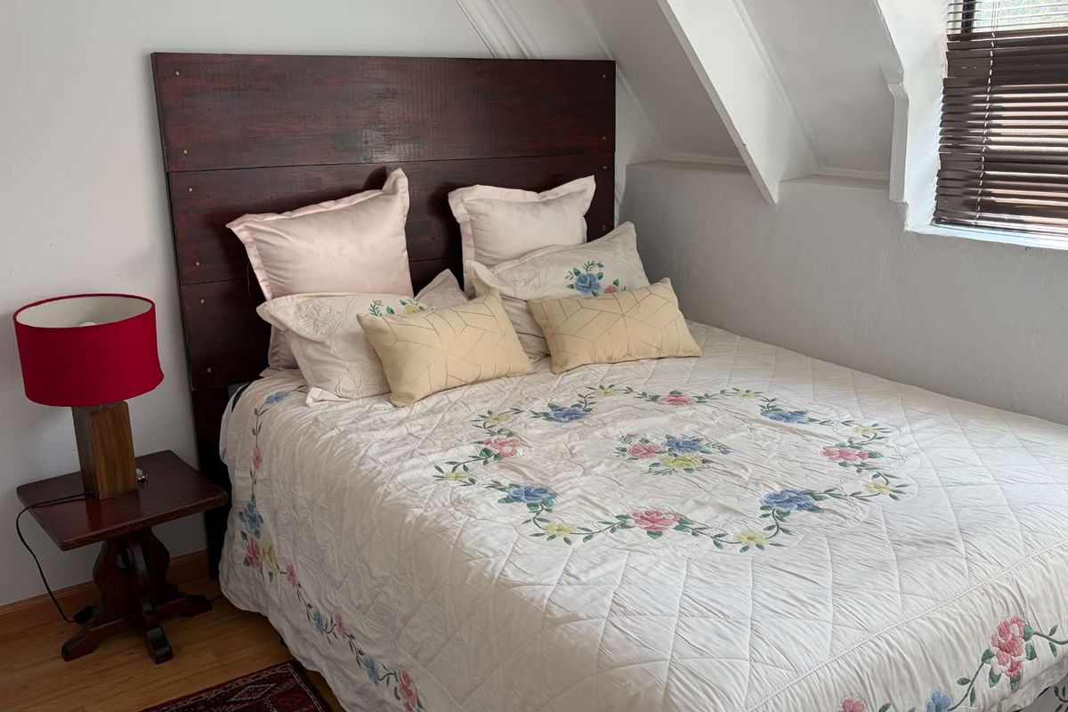 A cozy bedroom featuring a sloped ceiling, laminate flooring, and window blinds, offering a comfortable and functional living space.