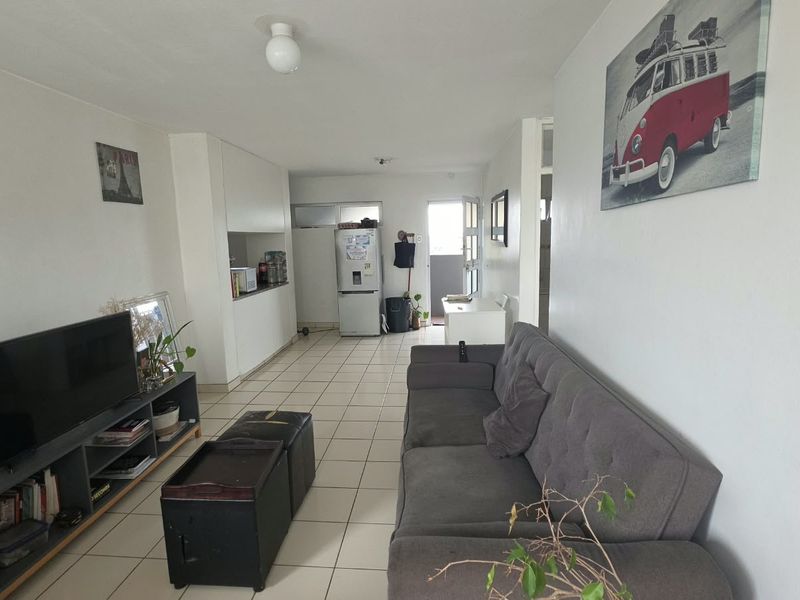 An open-plan living area featuring tiled flooring and a compact kitchen space, providing a functional layout for daily living.