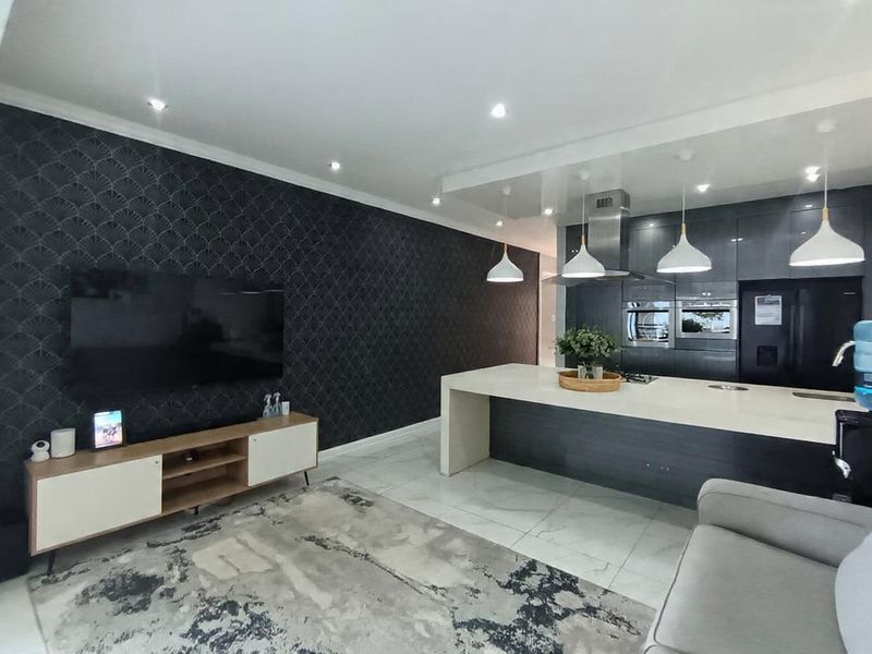 Modern open-plan living area featuring a sleek kitchen with a central island, built-in appliances, and contemporary finishes throughout.