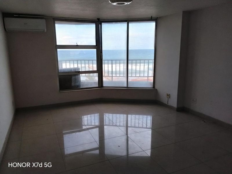 An empty living room featuring tiled floors, a split-system air conditioner, and large windows offering a direct view of the ocean.