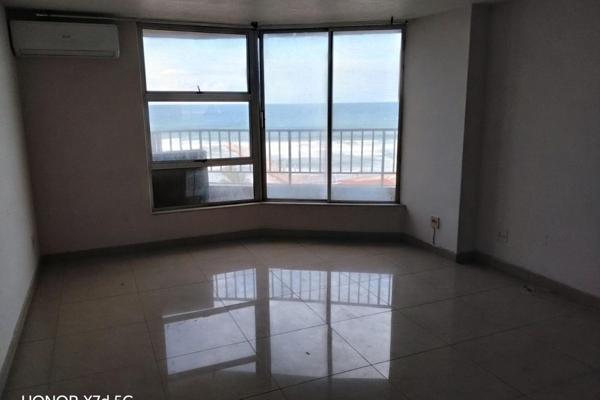 An empty living room featuring tiled floors, a split-system air conditioner, and large windows offering a direct view of the ocean.