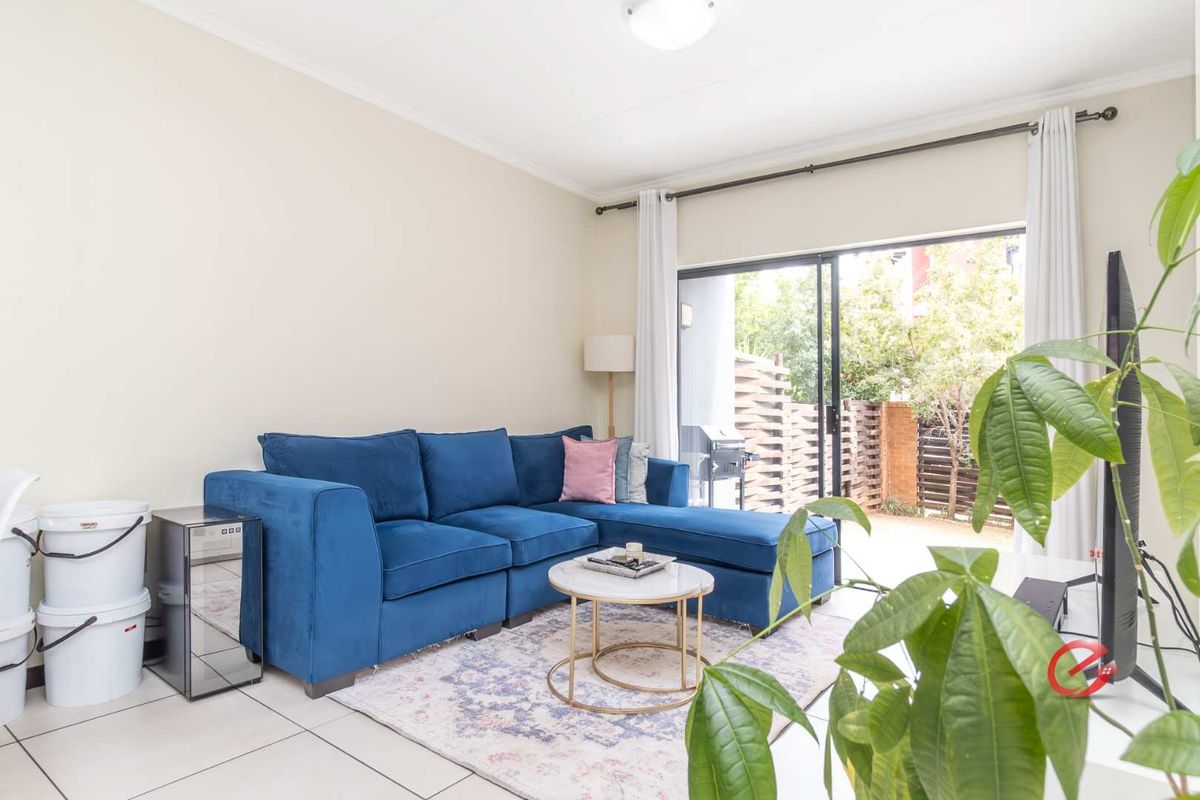 A bright living room featuring tiled flooring and large sliding glass doors that provide direct access to an outdoor patio area.