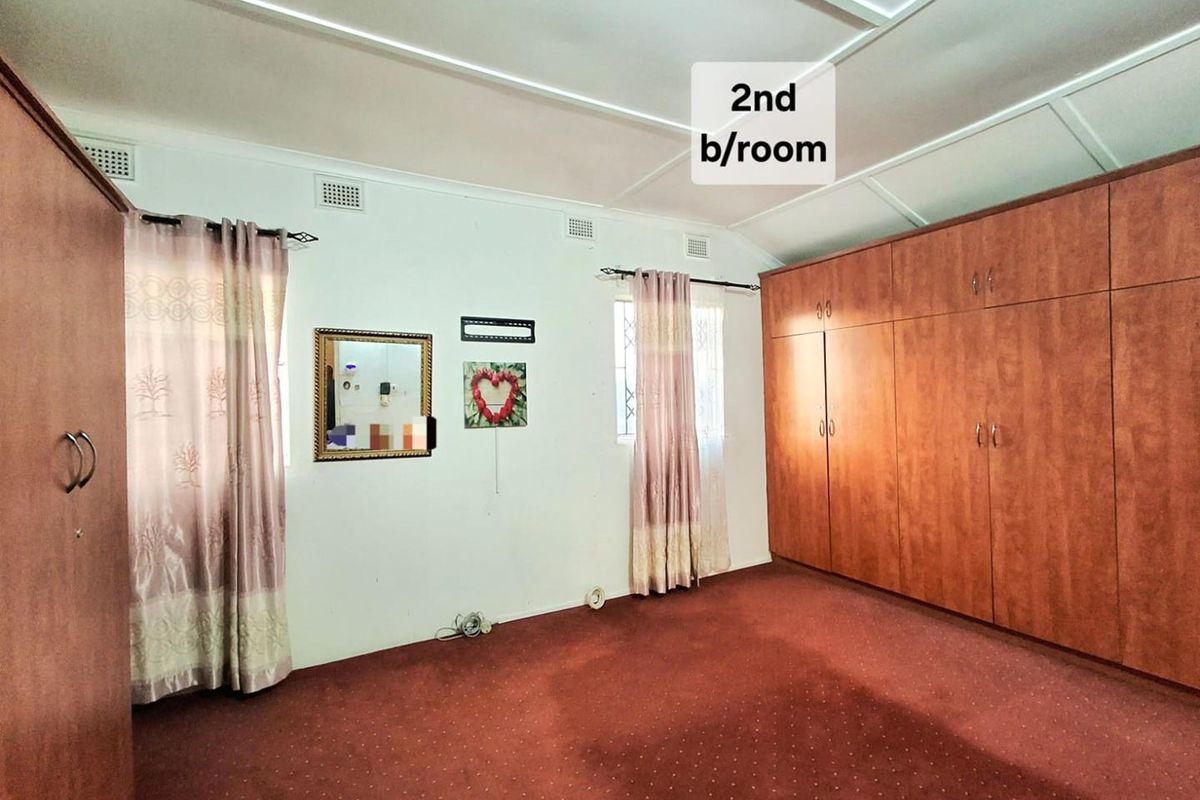 Spacious second bedroom featuring extensive built-in wooden cabinetry and carpeted flooring, offering a functional layout ready for modern updates.