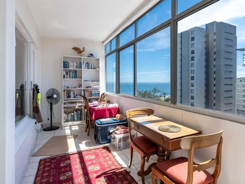Enclosed balcony featuring large windows with expansive ocean and coastal views, providing a bright and versatile space.