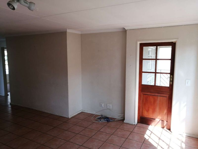 An empty living area featuring tiled flooring and a classic timber-framed glass door leading to an exterior space.