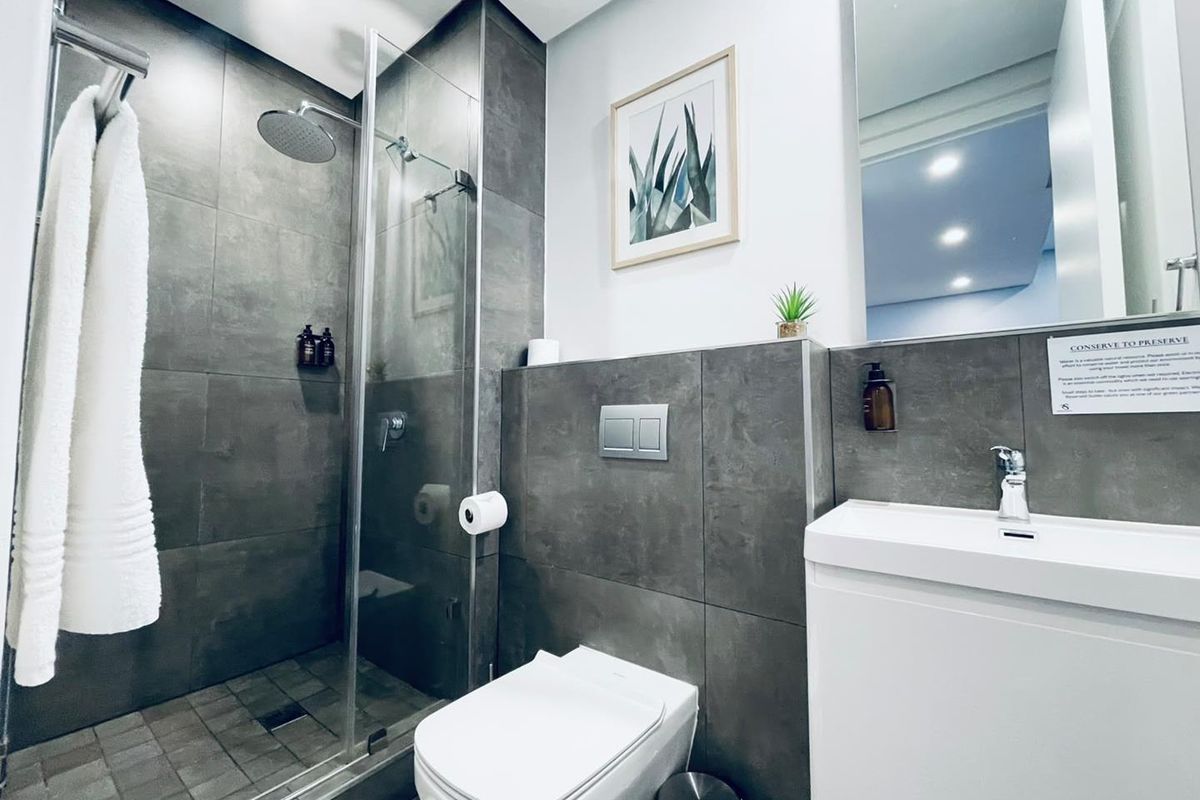 Modern bathroom featuring a walk-in shower with a rain shower head, wall-mounted toilet with concealed cistern, and a sleek vanity basin.