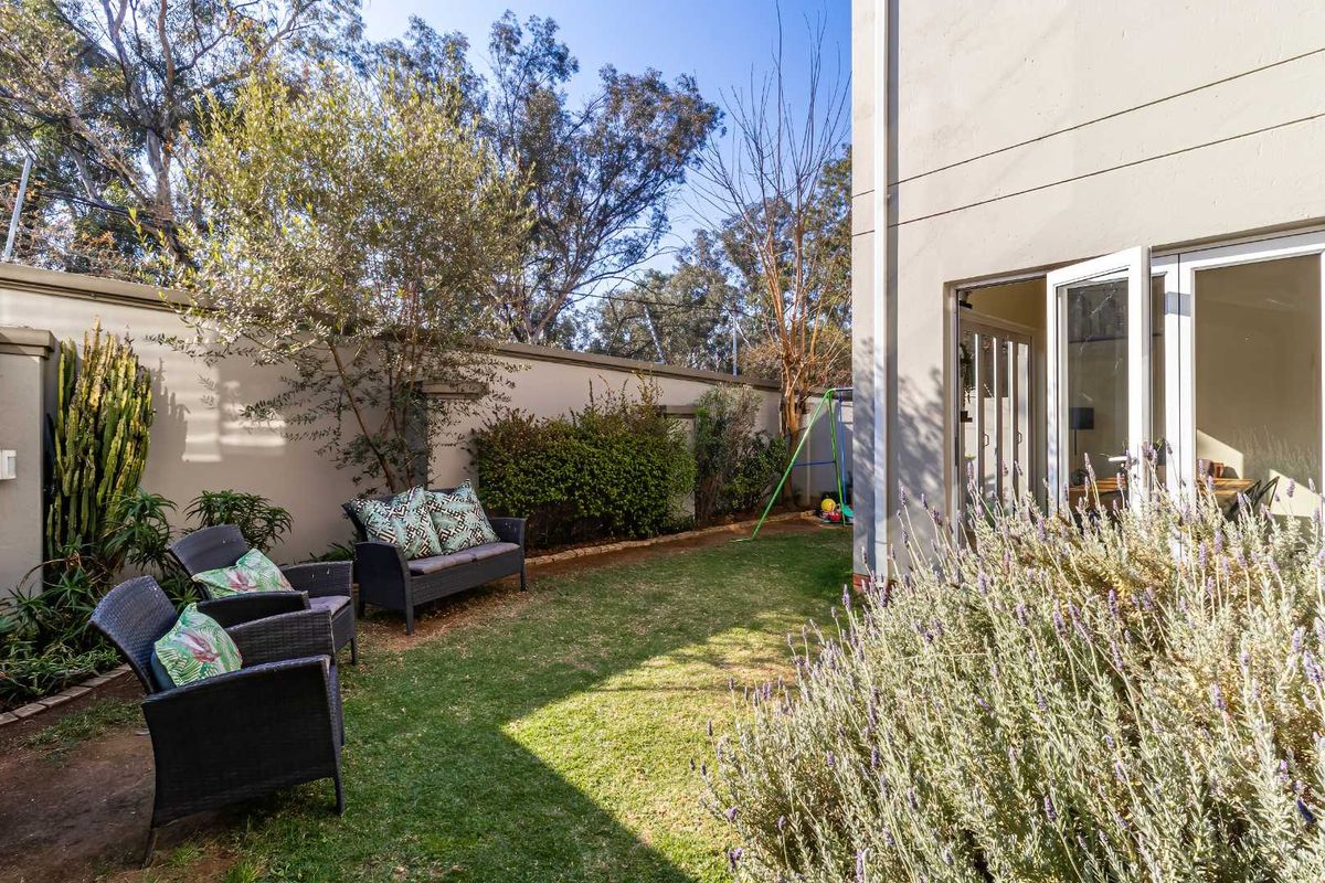 A private rear garden area featuring a well-maintained lawn, boundary wall, and direct access to the interior through double glass sliding doors.