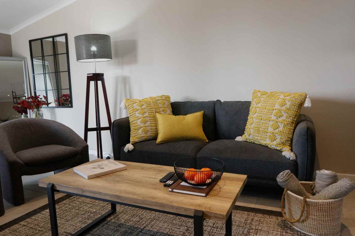 A well-maintained living room featuring neutral wall tones, tiled flooring, and decorative cove cornicing, creating a comfortable and inviting atmosphere.