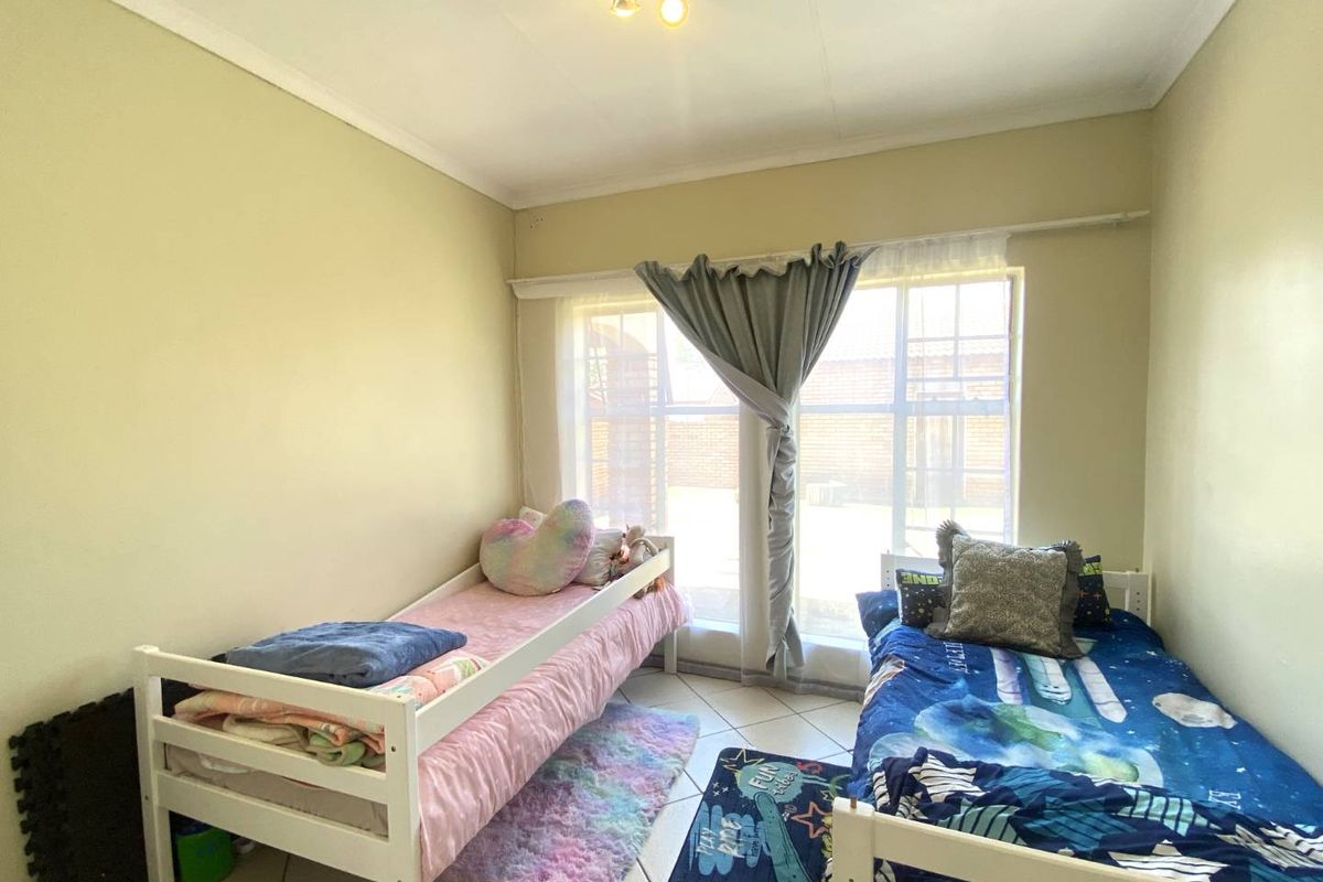 A functional bedroom featuring tiled flooring, large window with natural light, and standard ceiling lighting.