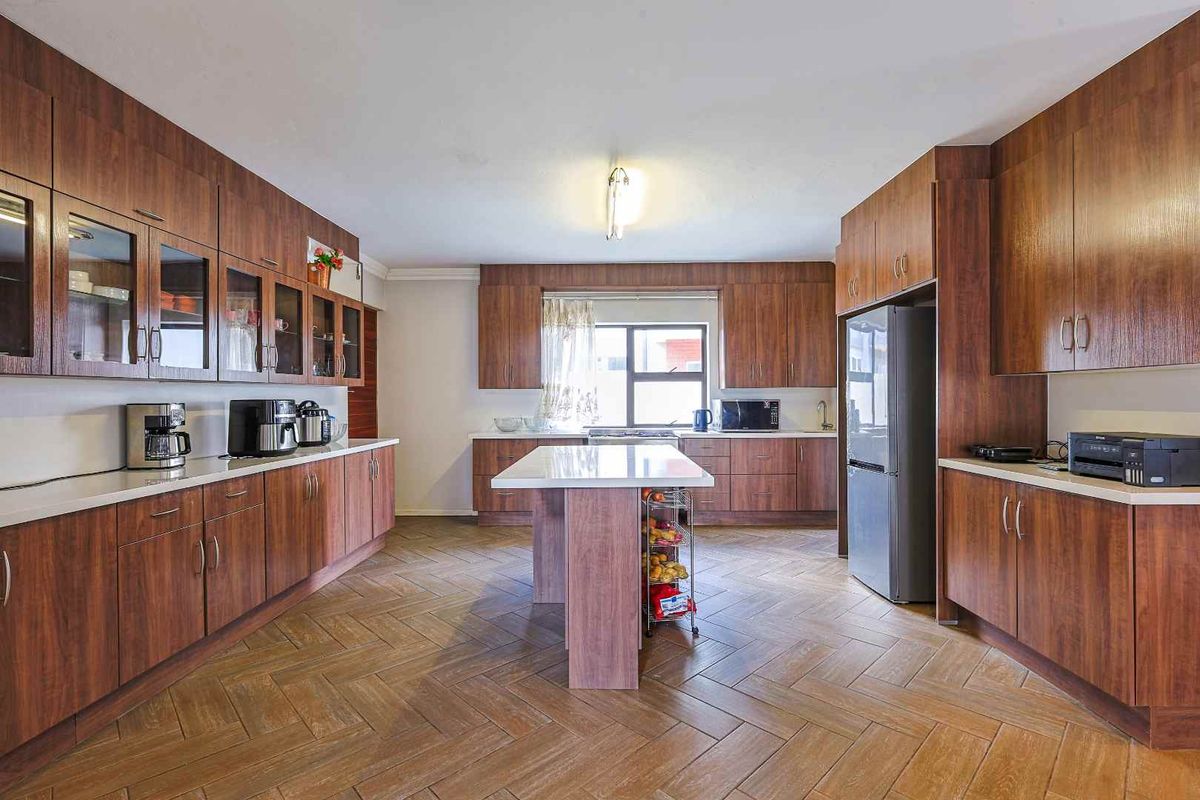 Spacious kitchen featuring extensive wood-finish cabinetry, a central island, and durable herringbone-patterned tiled flooring.