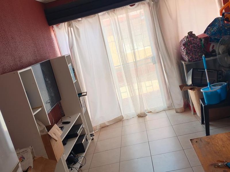 Living room area featuring tiled flooring and a sliding glass door leading to an outdoor space, with potential for cosmetic updates.