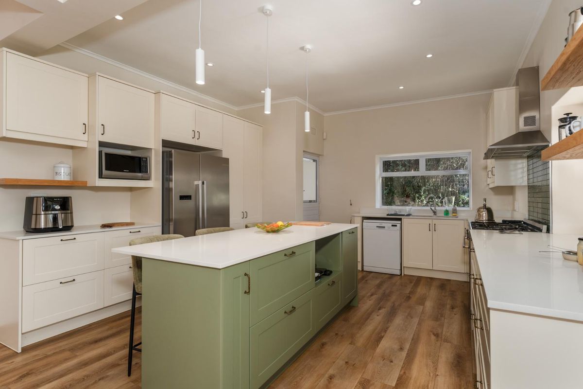 Modern, well-appointed kitchen featuring a central island with quartz countertops, integrated appliances, sleek cabinetry, and high-quality finishes throughout.