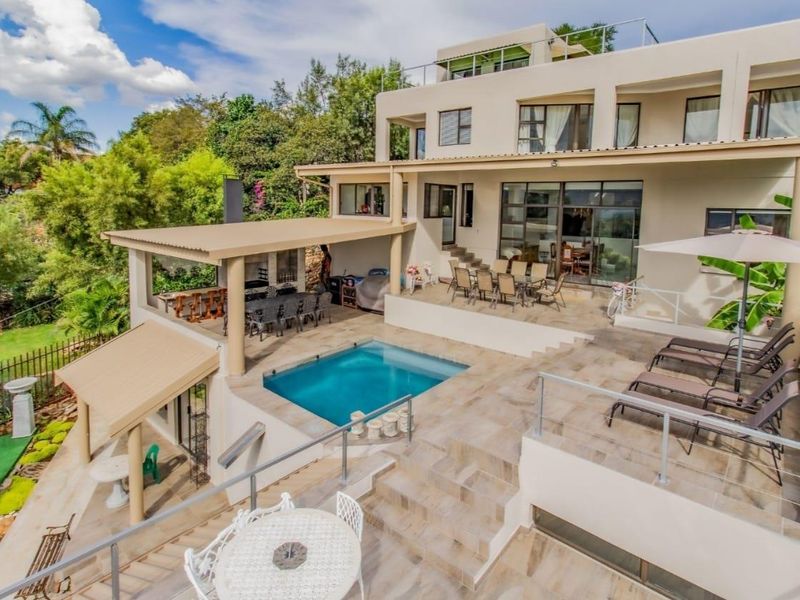 Spacious multi-level rear exterior featuring a swimming pool, covered patio area, and expansive tiled terrace, ideal for outdoor entertaining.