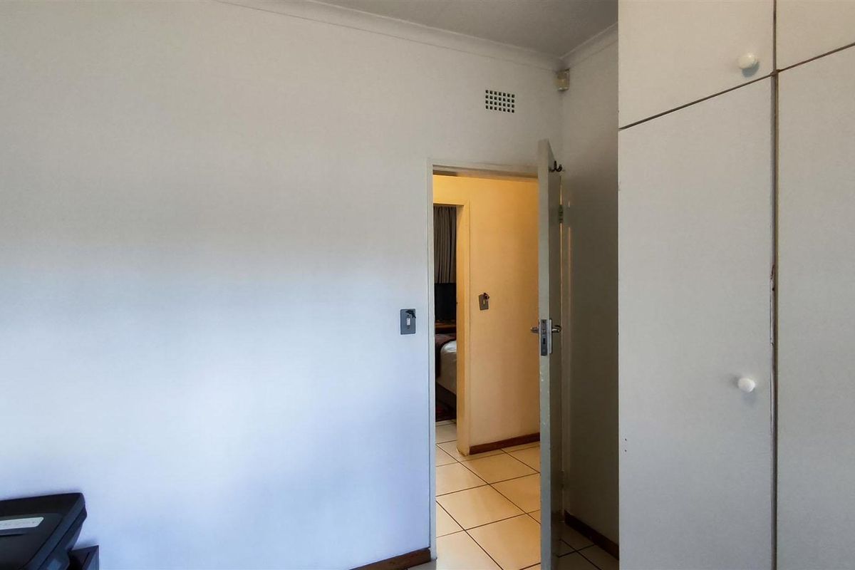 A simple bedroom featuring built-in cupboards and tiled flooring, offering a clean and neutral space ready for personalization.