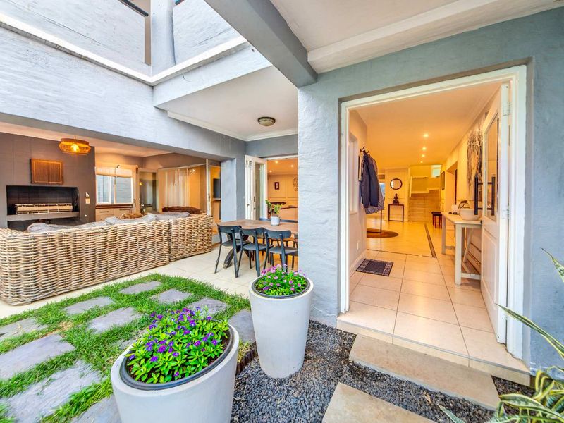 A spacious covered patio featuring a built-in braai, tiled flooring, and seamless flow into the interior living areas, perfect for outdoor entertaining.