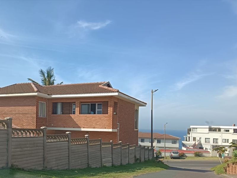 Exterior view of a face brick house featuring a tiled roof and secure precast boundary walling in a coastal neighbourhood setting.