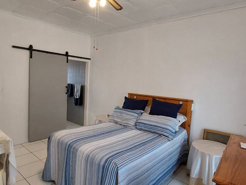 A bedroom featuring tiled flooring, a ceiling fan, and a sliding barn door leading to an adjacent space.