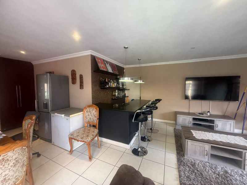 Open plan living area featuring a built-in bar counter with pendant lighting and tiled flooring throughout.