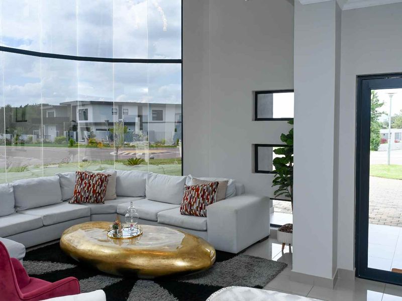 Spacious living area featuring floor-to-ceiling glass windows, high ceilings, and modern tiled flooring with direct access to the exterior.