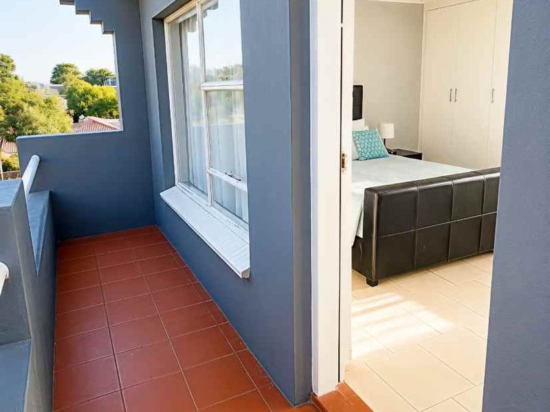 A private balcony with terracotta tiling, providing direct access to a bedroom featuring built-in cupboards and neutral flooring.