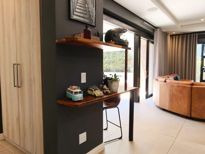 Modern open-plan living area featuring tiled floors, recessed lighting, built-in cabinetry, and a fireplace, seamlessly connecting to the outdoor space via sliding glass doors.
