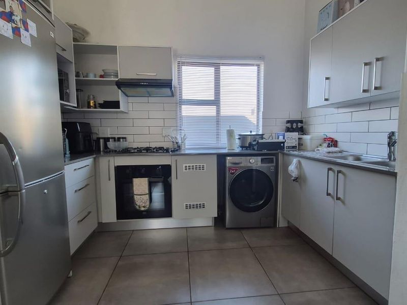 Modern kitchen featuring light grey cabinetry, subway tile backsplash, gas hob, built-in oven, and tiled flooring with integrated appliance space.