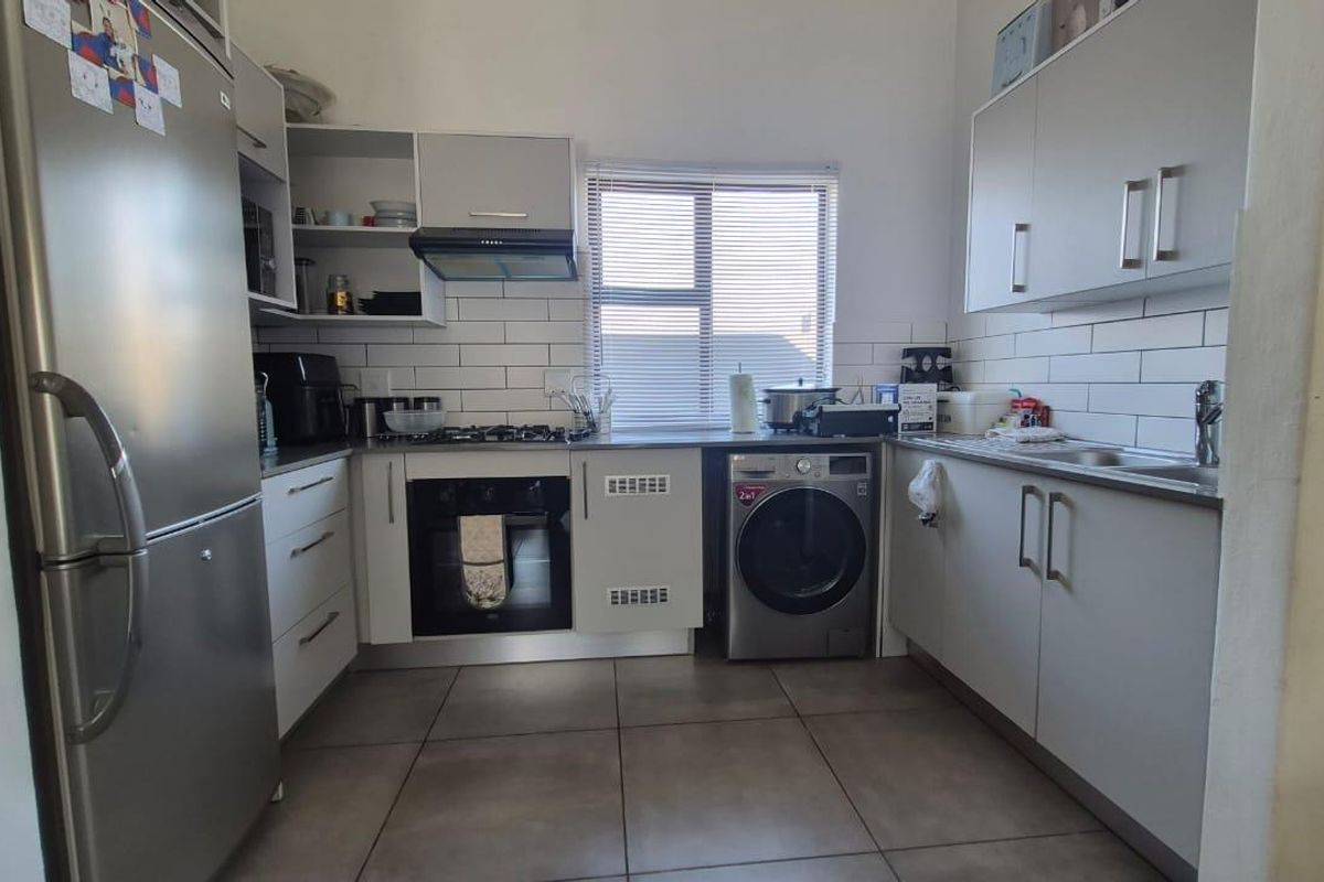 Modern kitchen featuring light grey cabinetry, subway tile backsplash, gas hob, built-in oven, and tiled flooring with integrated appliance space.