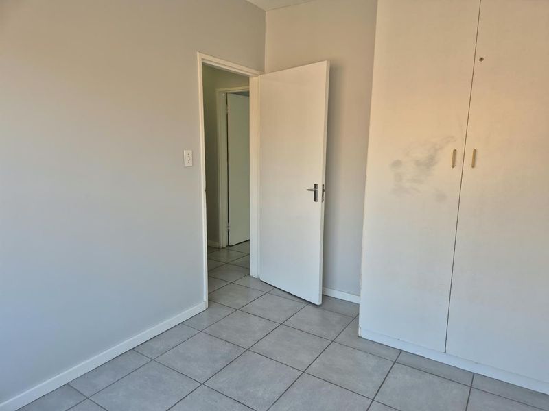 An empty bedroom featuring neutral tiled flooring and built-in cupboards, offering a clean, blank canvas for personalization.