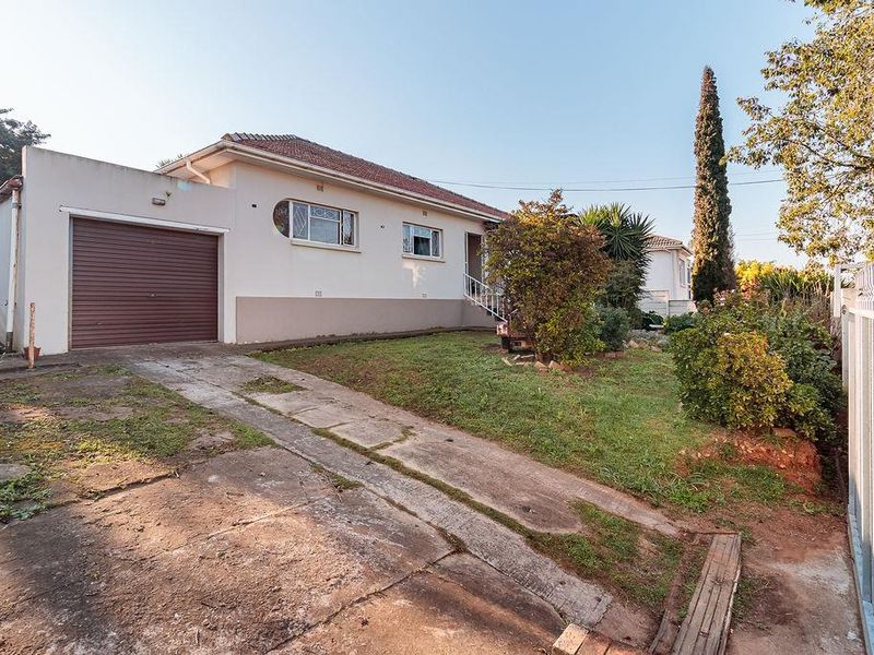 Front exterior view of a single-story house featuring a concrete driveway, single garage with a roller door, and a front garden area.