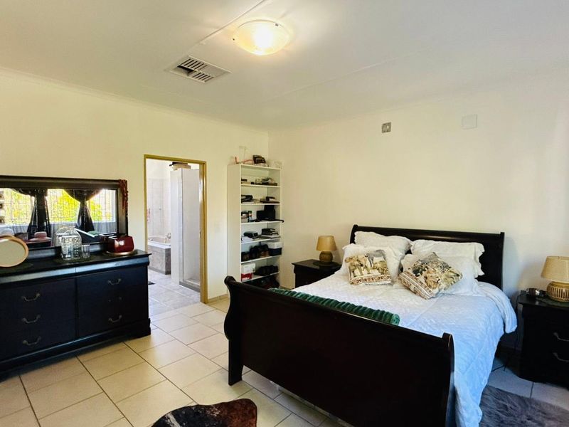A spacious bedroom featuring tiled flooring, a ceiling light, and direct access to an en-suite bathroom.