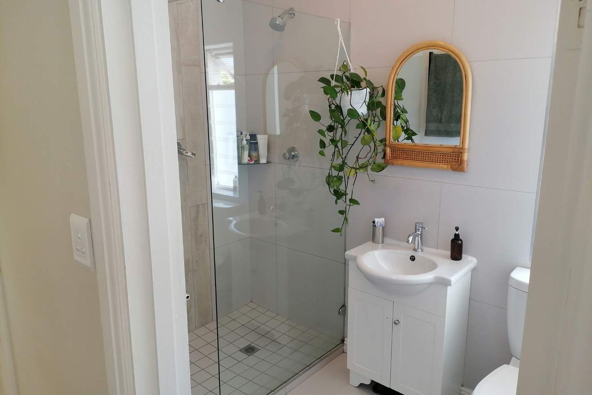 A modern bathroom featuring a glass-enclosed walk-in shower, a white vanity cabinet with a basin, and a standard toilet.