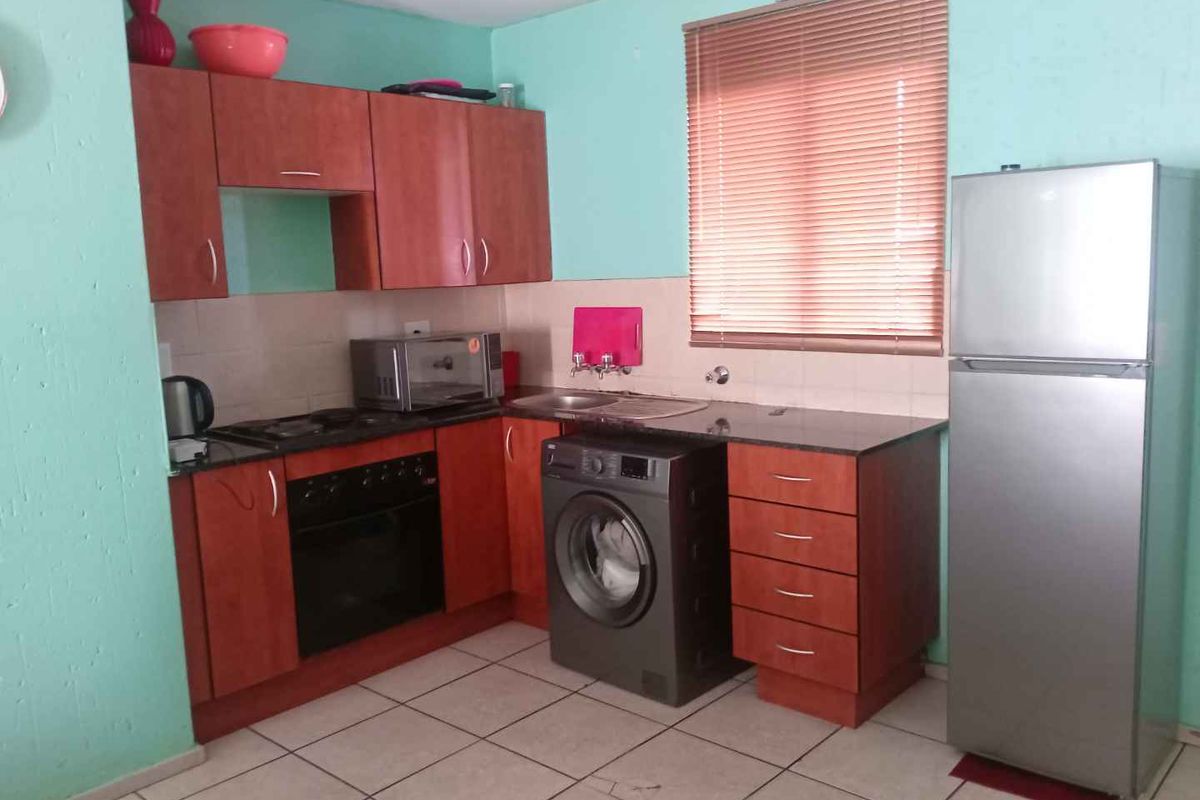 A functional kitchen featuring laminate cabinetry, granite countertops, a built-in oven, and tiled flooring, offering a practical layout for daily use.