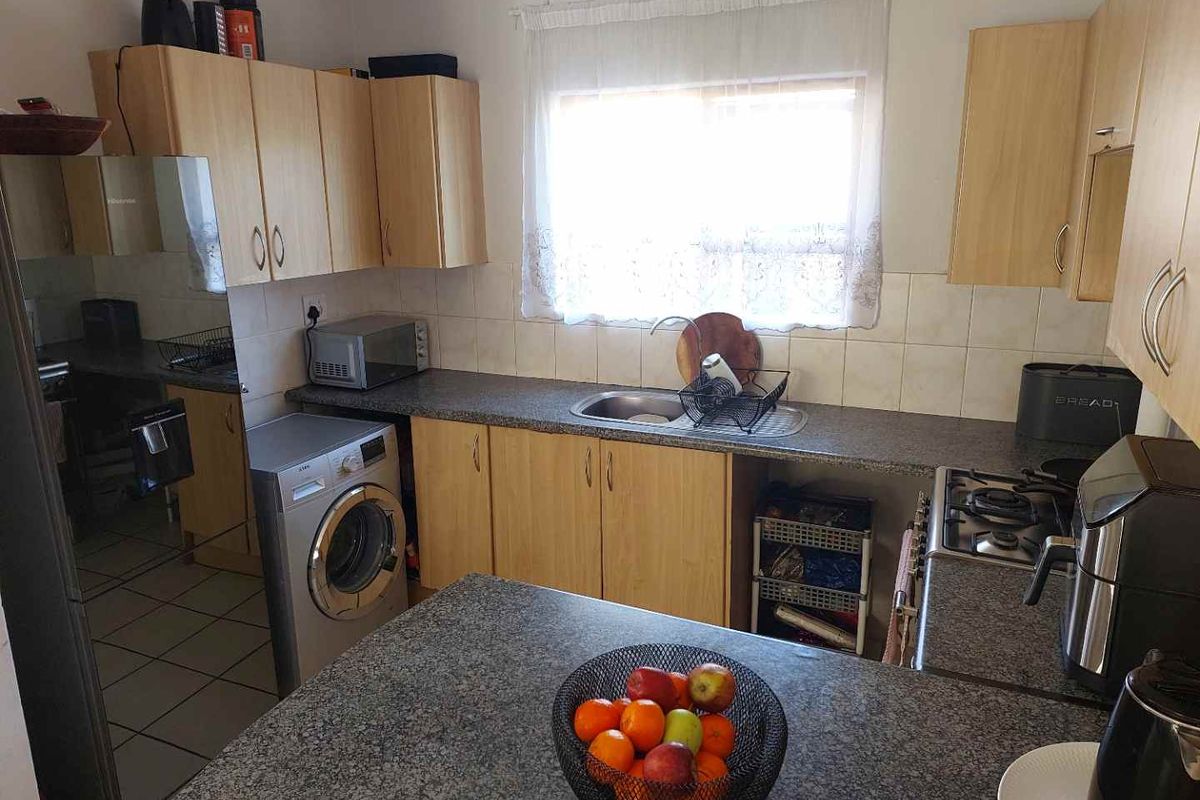 Functional kitchen featuring laminate cabinetry, granite countertops, a gas hob, and tiled finishes, providing a practical workspace for daily cooking and meal preparation.
