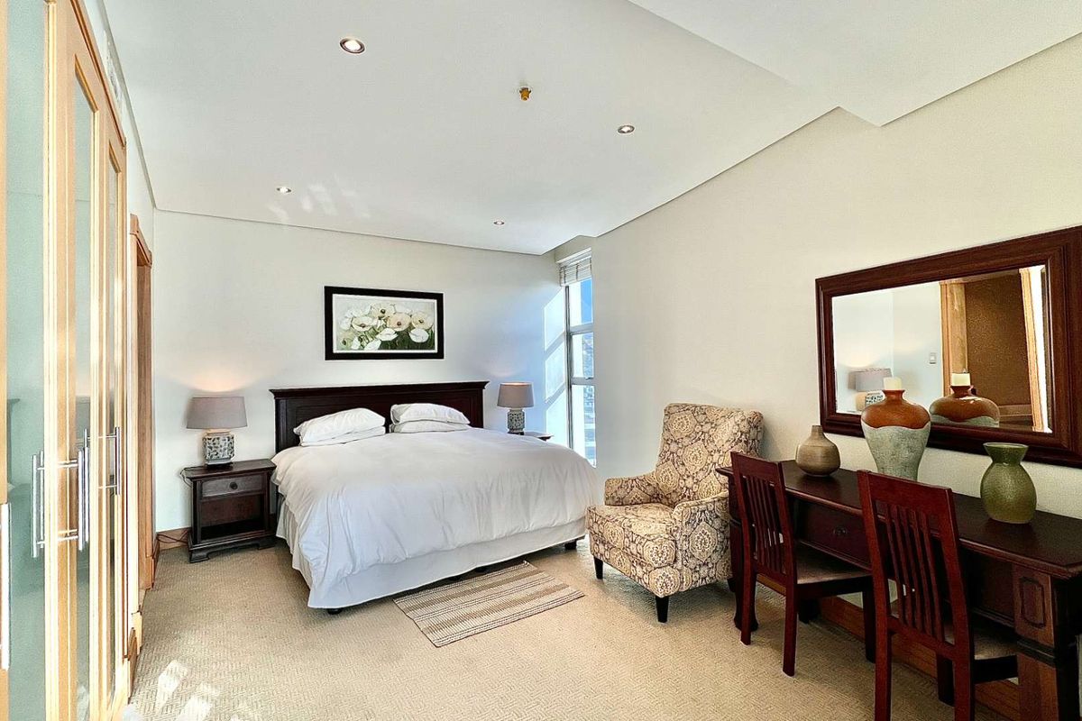 A well-maintained bedroom featuring built-in wooden cabinetry, recessed ceiling lighting, and neutral carpeting, offering a comfortable and functional living space.