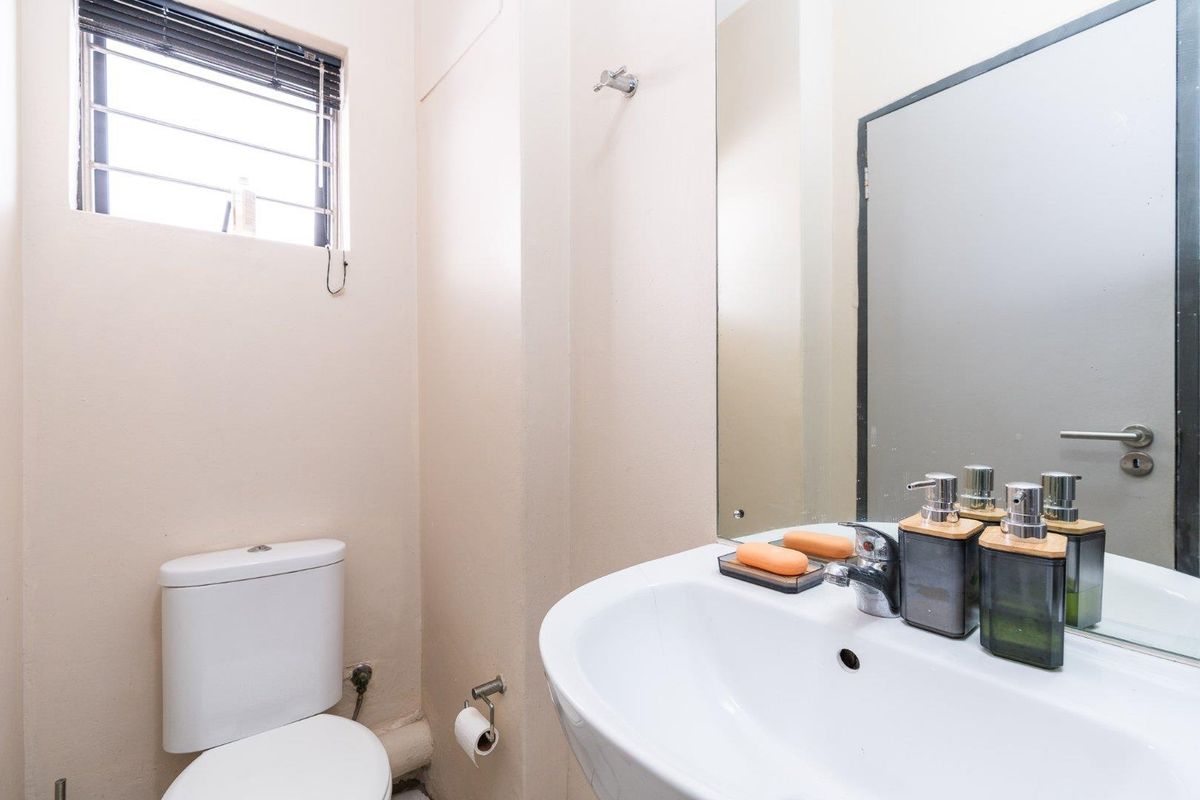 A functional bathroom featuring a white toilet, a pedestal washbasin with a chrome faucet, and a large wall-mounted mirror.
