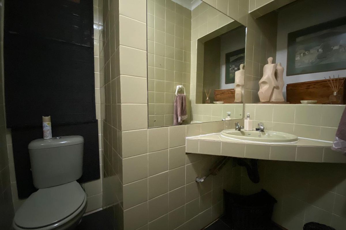 A compact bathroom featuring dated wall tiles, a built-in tiled vanity with a basin, and a standard toilet.