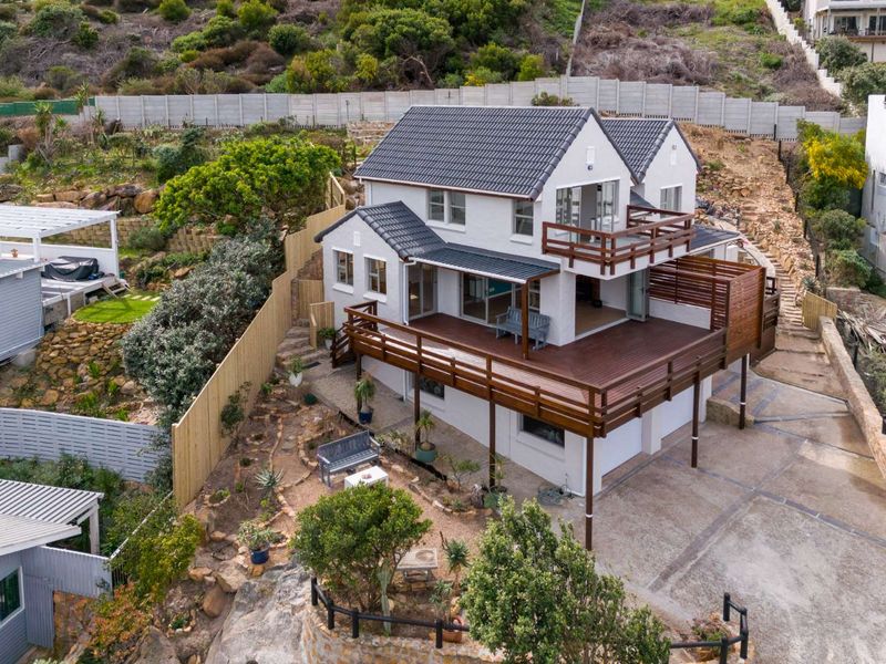 Aerial view of a multi-level residential property featuring a tiled roof, extensive timber decking, and landscaped terraced garden areas.