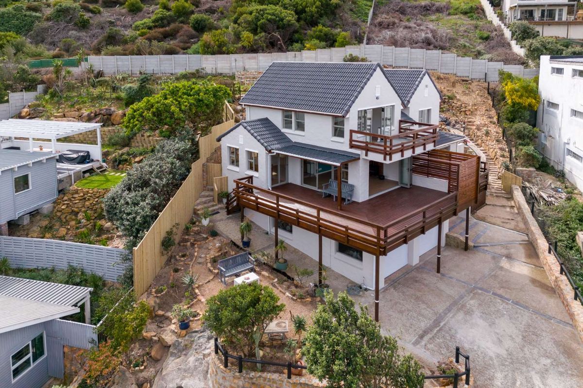 Aerial view of a multi-level residential property featuring a tiled roof, extensive timber decking, and landscaped terraced garden areas.