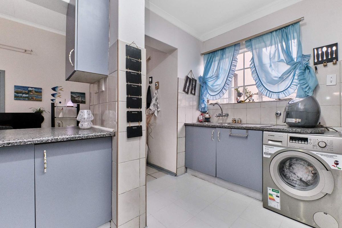 A functional kitchen featuring built-in cabinetry, granite-look countertops, a stainless steel sink, and dedicated space for a washing machine.
