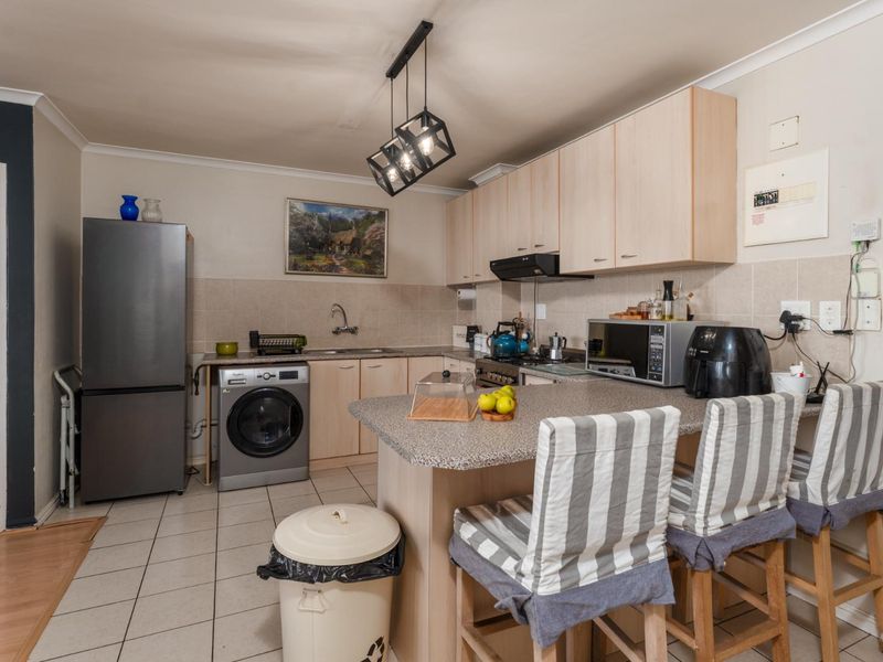 Functional kitchen featuring laminate cabinetry, a breakfast bar, tiled backsplash, and integrated extractor fan, offering a practical layout for daily use.