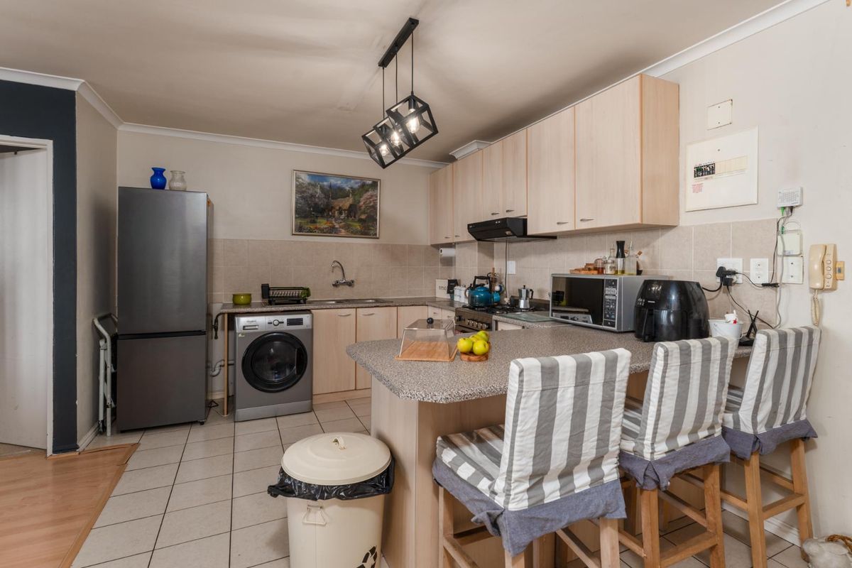Functional kitchen featuring laminate cabinetry, a breakfast bar, tiled backsplash, and integrated extractor fan, offering a practical layout for daily use.