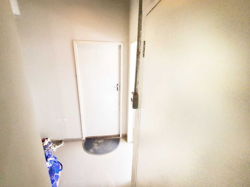 A simple, functional hallway space featuring a standard internal door and exposed electrical conduit along the wall.