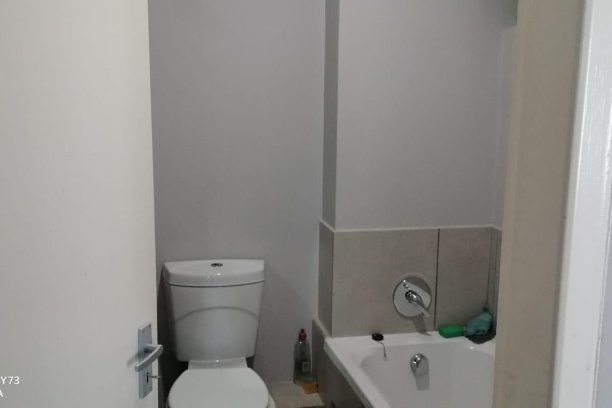 A functional bathroom featuring a standard toilet and a bathtub with integrated plumbing fixtures.