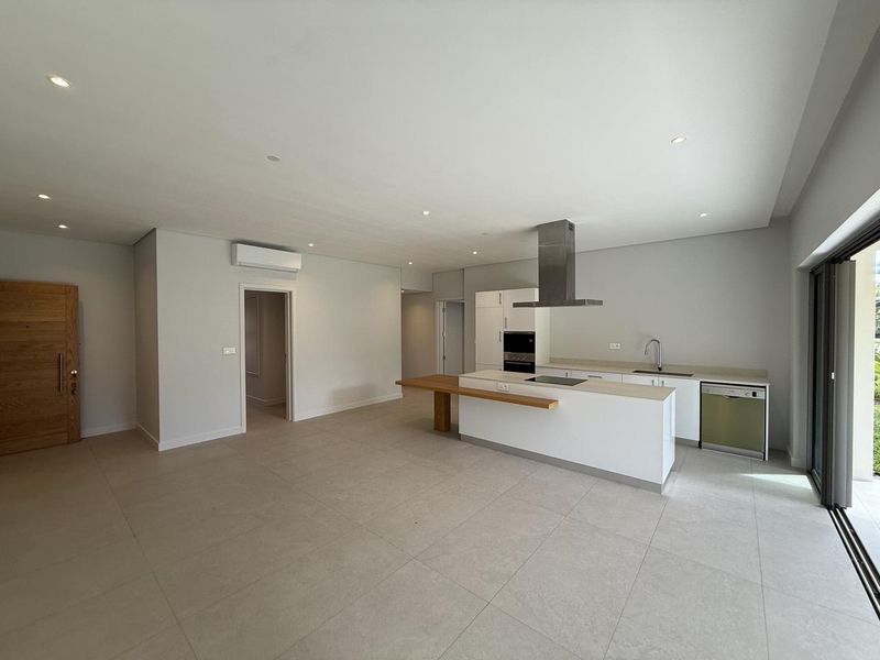 Spacious open-plan living and kitchen area featuring modern cabinetry, integrated appliances, tiled flooring, and large sliding doors leading to the outdoors.
