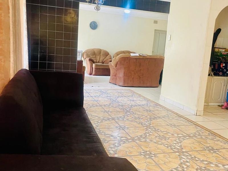 Spacious living area featuring decorative floor tiles, a feature tiled wall, and an archway leading to an adjacent room.